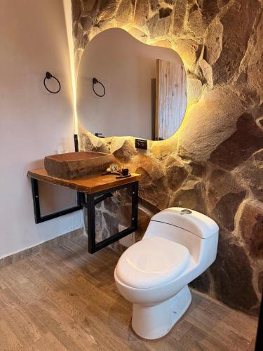 a bathroom with a white toilet and a mirror at Ecohotel Mauka in Pasto