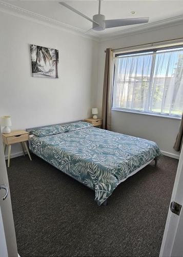 a bedroom with a bed and a large window at Beachcomber - 39 Phillip Drive South West Rocks in South West Rocks