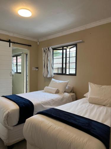 due letti in una stanza con due finestre di Crème de la crème Tiny Cottage a Durban