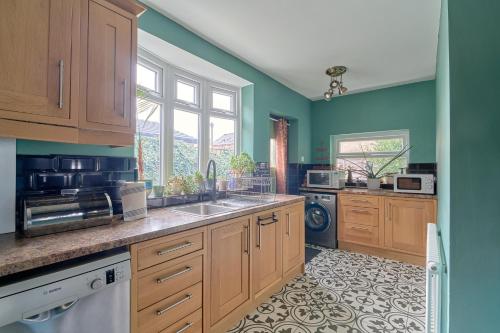 a kitchen with green walls and wooden cabinets and a sink at Home in Newcastle upon Tyne in Gosforth