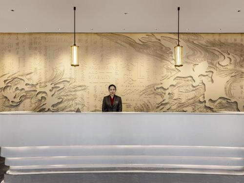 een man in pak die voor een muur staat bij Swissotel Beijing Hong Kong Macau Center in Beijing