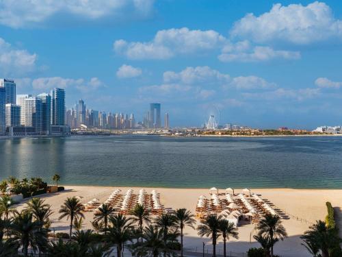 a beach with chairs and palm trees and a city at Fairmont The Palm in Dubai