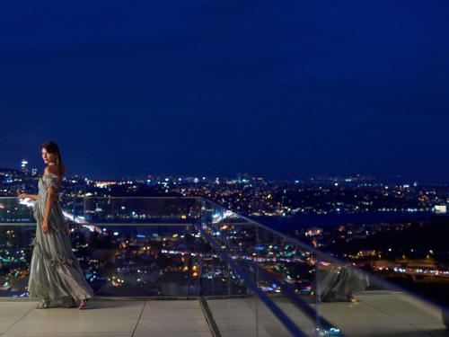 Una donna con un vestito in piedi sul bordo di un edificio di Raffles Istanbul a Istanbul