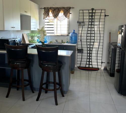 una cucina con 2 sgabelli da bar e bancone di New Cozy Entire home 2 Bedroom- AC, Wifi, 24 hour Security in Private Gated Community a Old Harbour