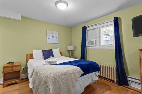 een slaapkamer met een bed met blauwe gordijnen en een raam bij Cozy Manor Studio Parking WiFi in St. John's