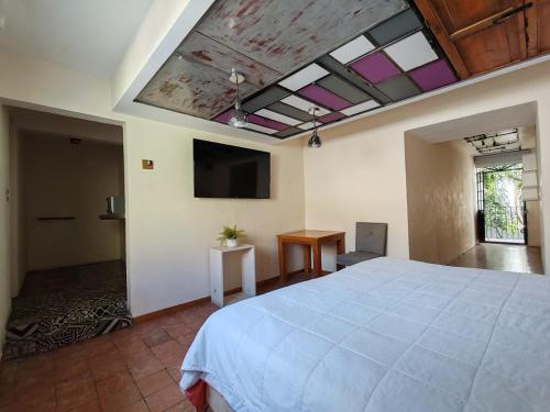 een slaapkamer met een groot bed en een flatscreen-tv bij Hostalgia in Puebla