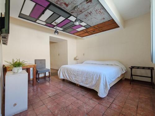 een slaapkamer met een bed en een plafond met ramen bij Hostalgia in Puebla