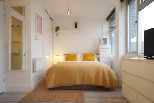 a bedroom with a bed with a yellow blanket at New Refurbish Studio to rent in Euston - Central London in London