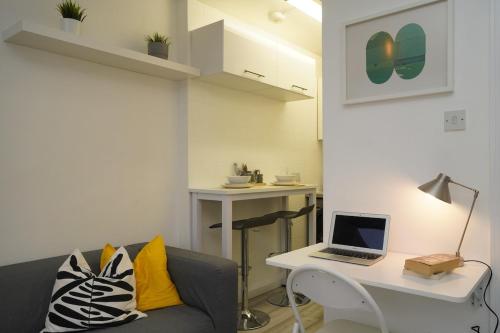 a living room with a couch and a laptop on a desk at New Refurbish Studio to rent in Euston - Central London in London