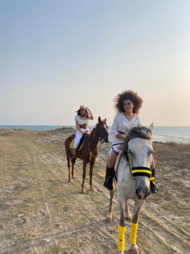 two women riding on horses on the beach at Forsen Kerkouen in Kerkouene
