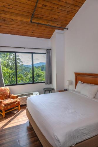 a bedroom with a bed and a chair and windows at Unicoi State Park & Lodge in Helen