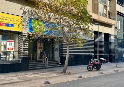 een motorfiets geparkeerd op een stoep voor een gebouw bij Apart Merced Home in Santiago
