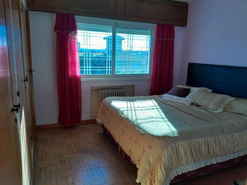a bedroom with a bed with red curtains and a window at Alquiler temporal Casa céntrica in La Falda