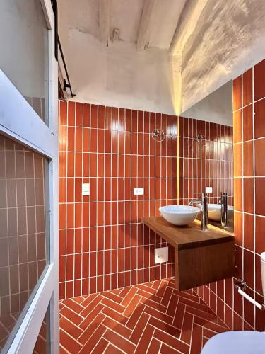 a bathroom with a sink and orange tiled walls at Runa Barichara in Barichara