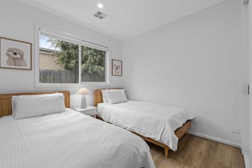 deux lits dans une chambre blanche avec une fenêtre dans l'établissement Luxe Coastal Retreat, à St Leonards