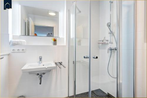 a white bathroom with a shower and a sink at Ostseenest Bernstein in Kölpinsee