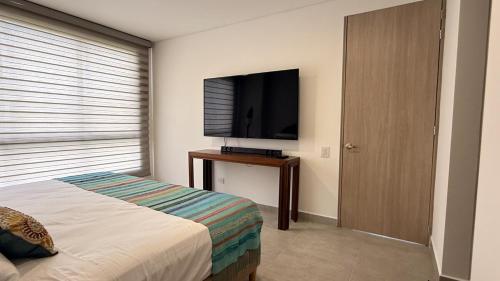 a bedroom with a bed and a flat screen tv at Apartamento Campestre 6 Pax in Armenia