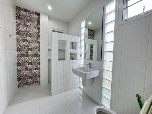 un bagno bianco con lavandino e specchio di Villa88 สันกำแพงสายใหม่ 