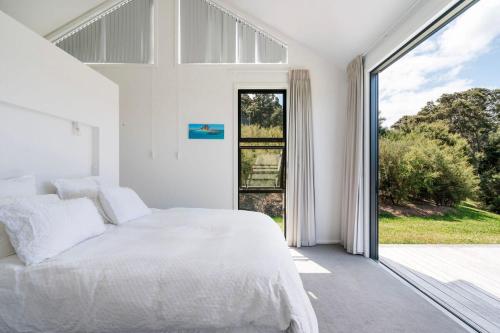 een slaapkamer met een wit bed en een groot raam bij Bishop's Lane in Sandspit