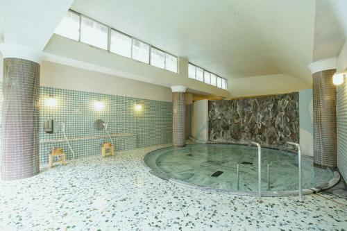 a large tub in a room with a stone wall at Bansuirou Fukuzumi in Hakone