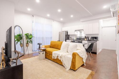 a living room with a yellow couch and a kitchen at Stylish Retreat Near Crescent & Sainte-Catherine in Montréal