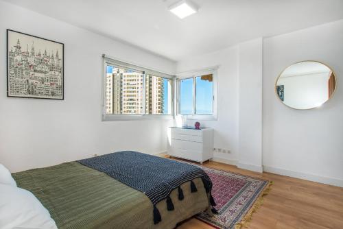 una camera da letto bianca con un letto e uno specchio di Magnífico Sol Paraíso ad Adeje