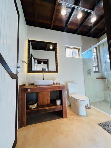 a bathroom with a sink and a toilet and a mirror at Studio Na Natureza Com Hidro - Baoba Suites in Bombinhas
