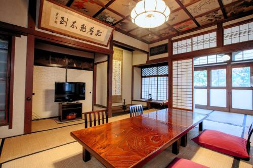 a dining room with a wooden table and a television at Bansuirou Fukuzumi in Hakone