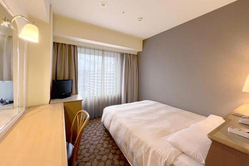 a hotel room with a bed and a desk and a television at Hotel Fujita Fukui in Fukui