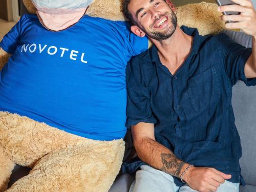 een man op een bank met een teddybeer bij Novotel Malta Sliema in Il-Gżira