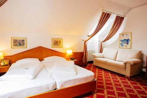 a hotel room with two beds and a couch at Hotel Kongress in Leoben