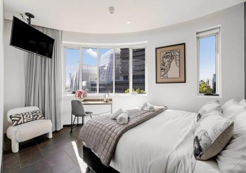 a white bedroom with a large bed and a chair at Spice On Broadway in Sydney