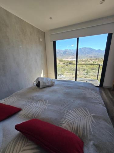 una camera da letto con un letto grande con una grande finestra di Altos Dique Potrerillos a Potrerillos