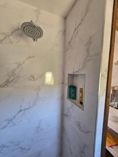 e bagno con pareti in marmo bianco e doccia. di Altos Dique Potrerillos a Potrerillos