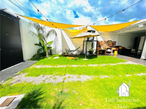een patio met een parasol en een grasveld bij Loft Industrial Petfriendly in Tlaxcala de Xicohténcatl