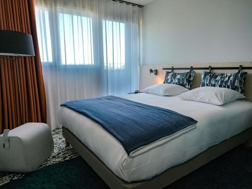 een slaapkamer met een groot bed met een blauwe deken bij ibis Styles Bordeaux Lac Bruges in Bordeaux