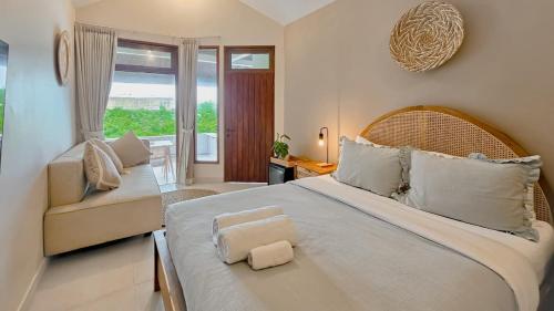 ein Schlafzimmer mit einem großen weißen Bett und einem Stuhl in der Unterkunft Uluwatu Ocean Front Surf Suite in Uluwatu