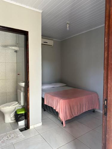 a small bedroom with a bed and a toilet at Casa Aiyra in São Miguel dos Milagres