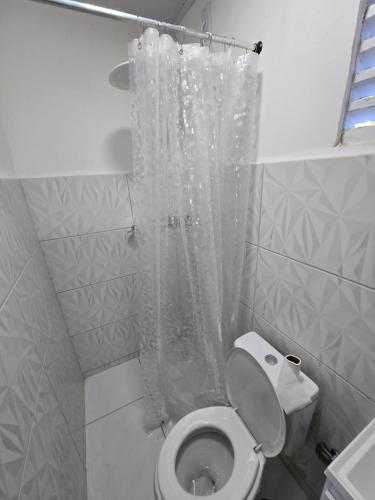 a bathroom with a toilet with a shower curtain at Pousada Hostel Beach Pajuçara in Maceió