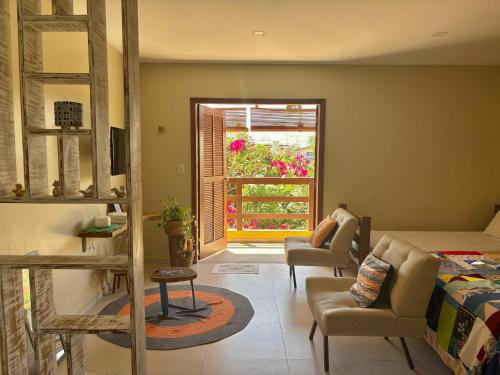 een slaapkamer met een bed, stoelen en een raam bij Quintal da Espera - Praia de Itacimirim in Camaçari