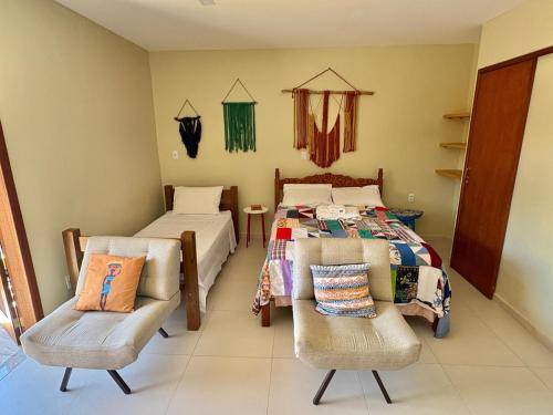 een kamer met twee bedden en twee stoelen erin bij Quintal da Espera - Praia de Itacimirim in Camaçari