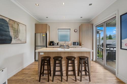 a kitchen with a island with bar stools at Cardrona Villa with Pool and Jacuzzi in Cardrona