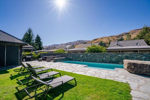 a backyard with lounge chairs and a swimming pool at Cardrona Villa with Pool and Jacuzzi in Cardrona