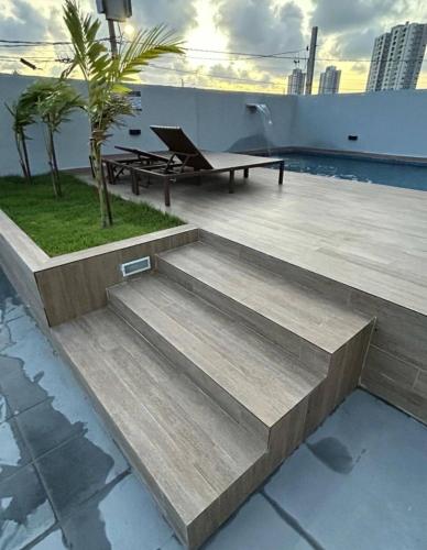 eine Terrasse mit einer Bank auf dem Dach eines Gebäudes in der Unterkunft Conforto e sofisticação em Ponta de Campina in Cabedelo