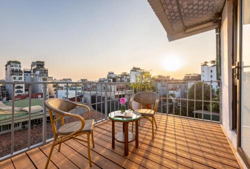2 stoelen en een tafel op een balkon met uitzicht bij Golden Legend Palace Hotel & Travel in Hanoi