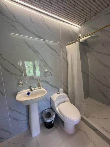 a white bathroom with a sink and a toilet at The Jungle Cocoon in Nueva Loja