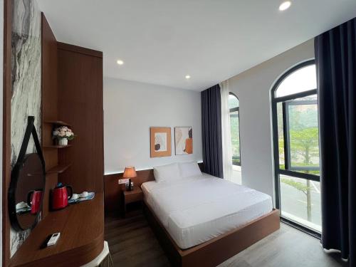 a bedroom with a bed and a large window at Kapás Hotel in Hai Phong