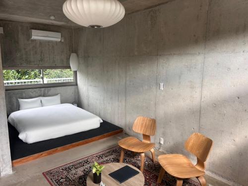 ein Schlafzimmer mit einem Bett und zwei Stühlen und einem Tisch in der Unterkunft Stay Hotel Nakijin in Nakijin