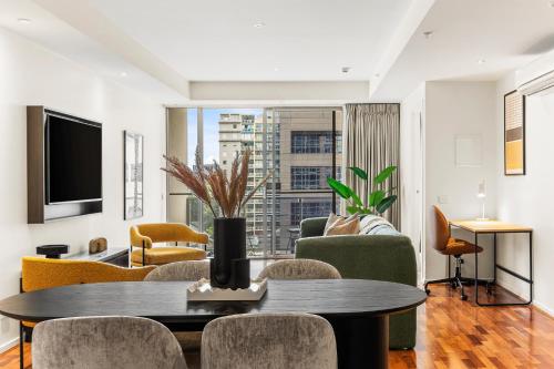 a living room with a table and chairs at Nolo Apartments Lonsdale St in Melbourne