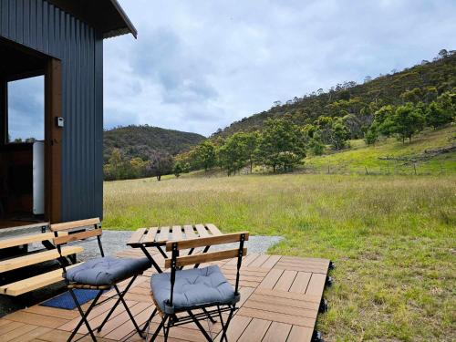 a wooden deck with two chairs and a picnic table at Anakie Gorge Getaway Tiny House 1 by Tiny Away in Staughton Vale